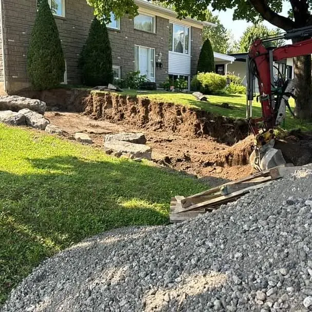 Excavation de terrain avec une mini-excavatrice devant une résidence